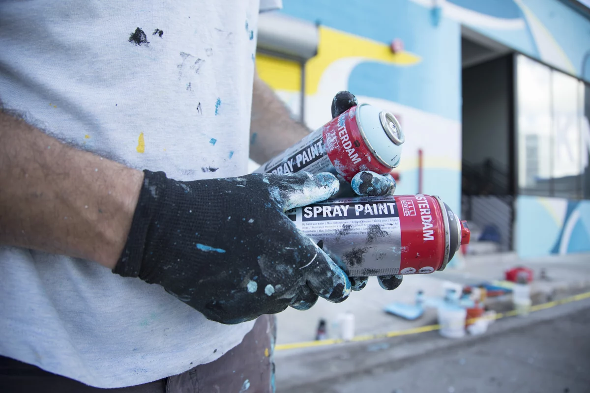 Main tenant une bombe Amsterdam Spray Paint devant un mur — Royal Talens