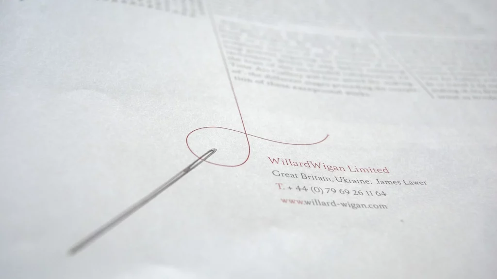 Aiguille et fil rouge sur une page du journal